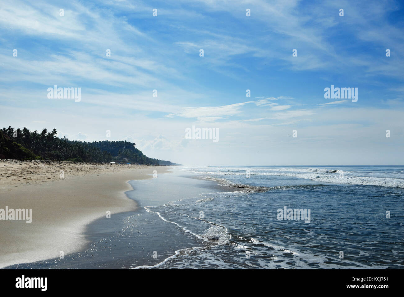 Der lange Strand ist in den Horizont mit kleinen Wellen und Haze. Stockfoto