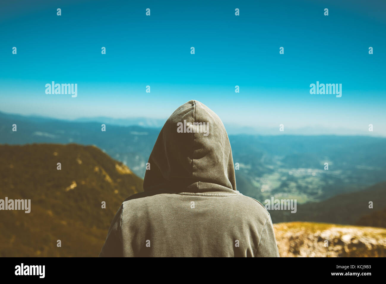 Nicht erkennbare weibliche Person bei hohen Berg Sicht. Rückansicht der jungen erwachsenen Frau tragen Hoodie in der Ferne am Horizont suchen. getönt Stockfoto