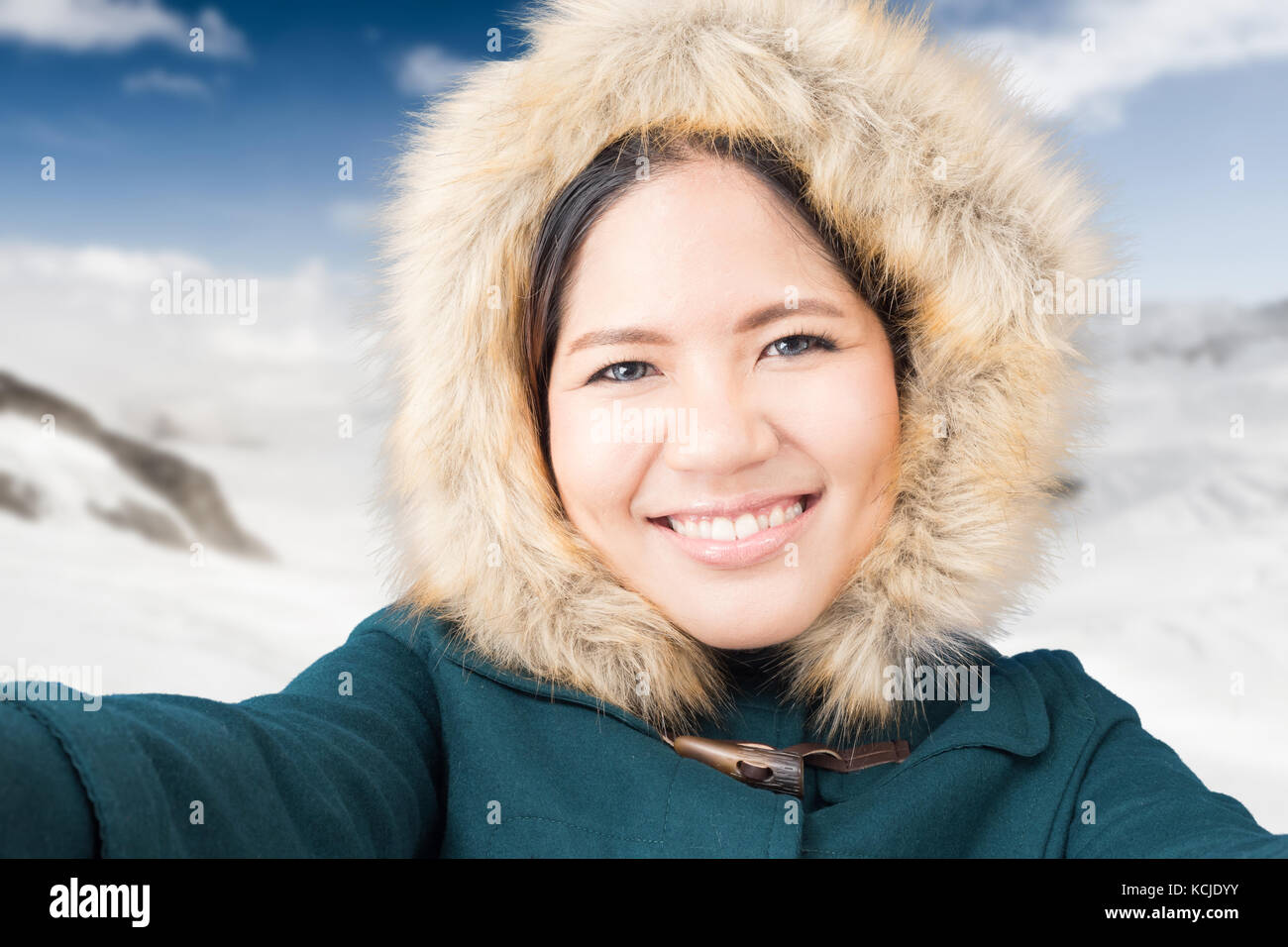 Asiatische Touristen Tragen von grünen Mantel mit Snow Mountain Hintergrund Stockfoto