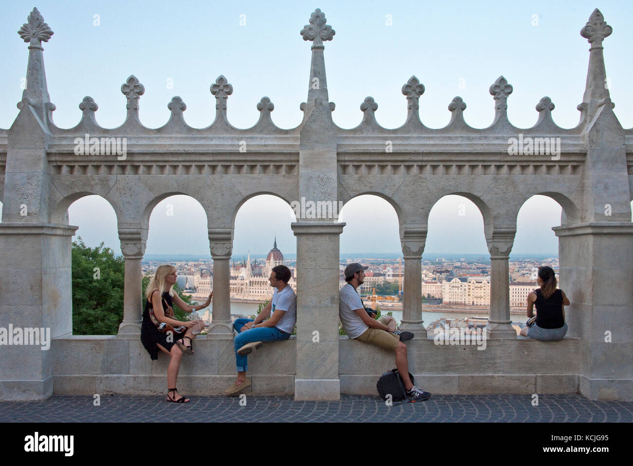 Vier 4 Personen, zwei 2 Paare Touristen an den Wänden der Fischerbastei bewundern die Aussicht auf Budapest mit blauem Himmel, wie die Sonne untergegangen ist. Stockfoto