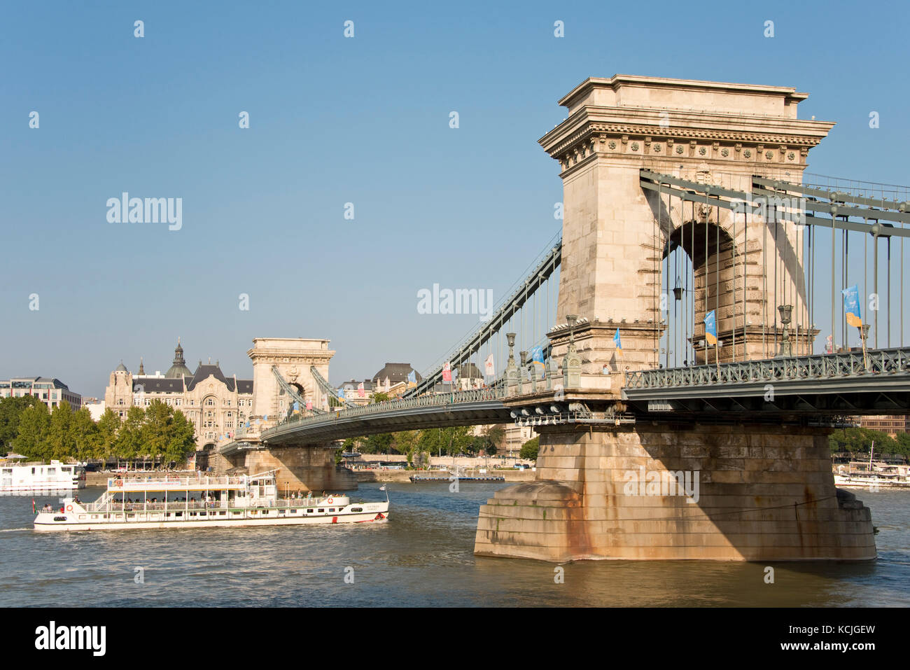 Ein Blick auf die Széchenyi Kettenbrücke in Budapest mit einer Tagesfahrt Flusskreuzfahrt Boot unter an einem sonnigen Tag mit blauem Himmel vorbei. Stockfoto