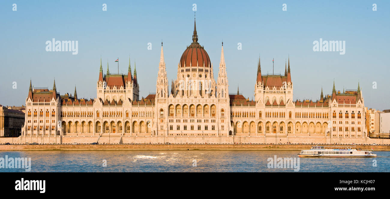 3-Bild-Maschenpanorama des ungarischen Parlamentsgebäudes an der Donau in Budapest mit einem Flussschiff, das vorbeifährt. Stockfoto