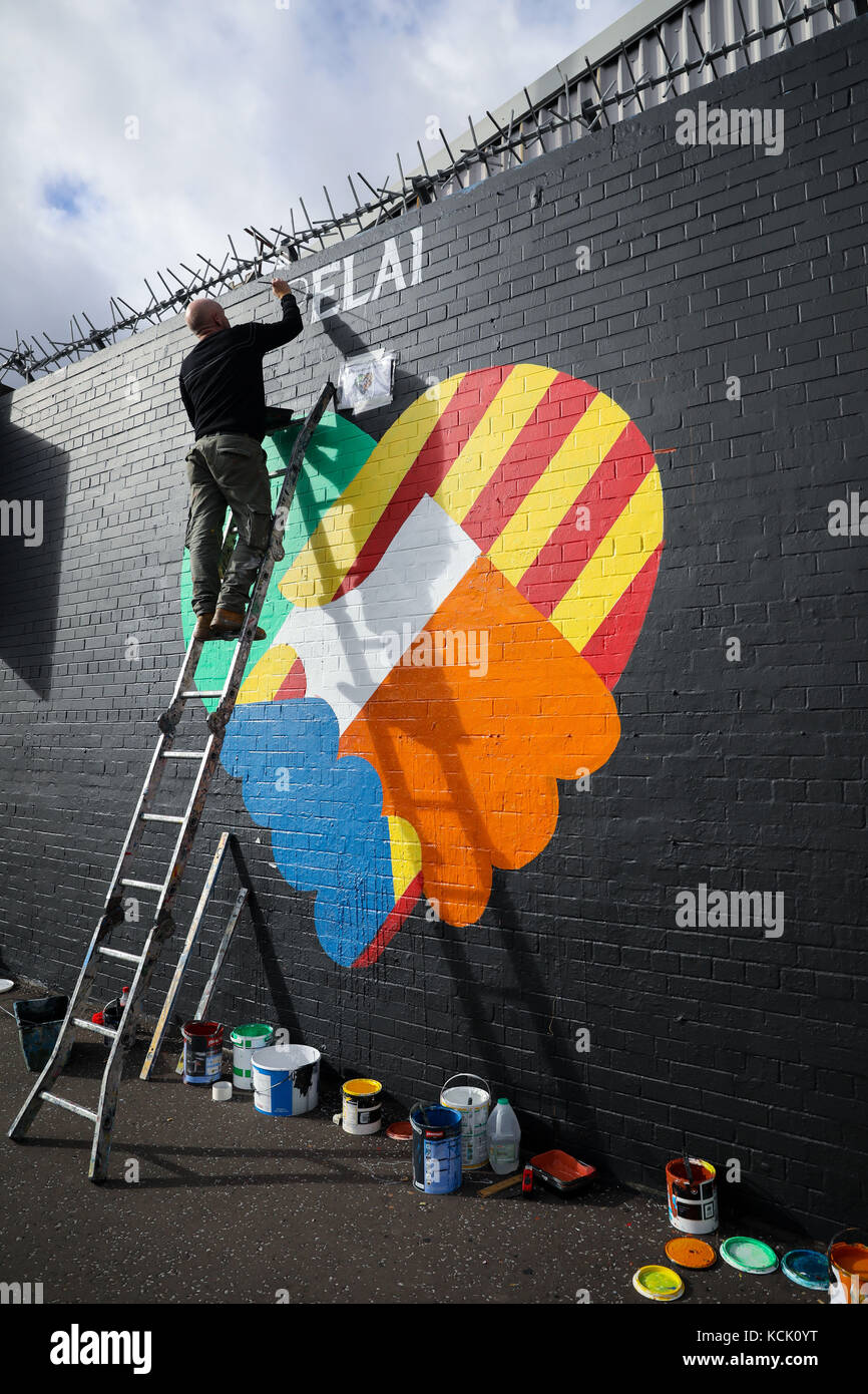 Belfast, Nordirien. Oktober 2017. Zwei irische republikanische Kunstaktivits greifen auf eine Mauer an der „International Wall/Divis Street“ zurück, um die Indepedenzbewegung in Katalonien, in Belfast, Nordirien, am 5. Oktober 2017 zu unterstützen. Die Briefe lauten: "Irland steht mit Katalonien". Quelle: Christian Charisius/dpa/Alamy Live News Stockfoto