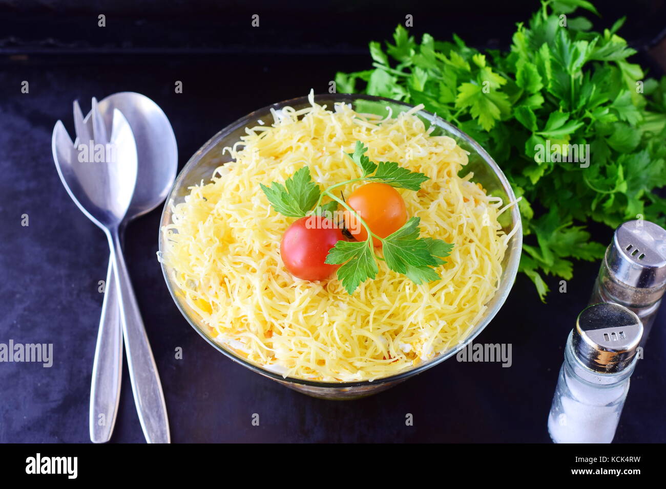 Salat mit Huhn Leber in Schichten mit Gurken, gekochte Karotten, Eier, Käse in eine Glasschüssel auf einem schwarzen Abstrakt Hintergrund. top anzeigen. Gesundes Essen conc Stockfoto