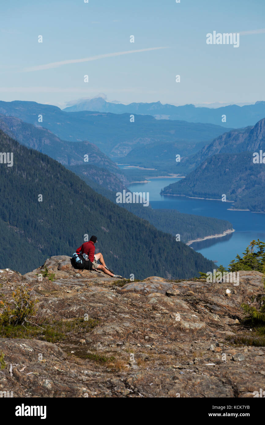 Ein einbeinter männlicher Wanderer entspannt sich an einem Aussichtspunkt auf dem Flower Ridge Trail mit Blick auf den Buttle Lake im Strathcona Park. Vancouver Island, British Columbia, Kanada Stockfoto