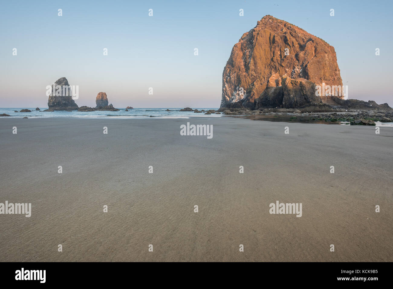 Haystack rocks ragt über Küste mit Sandstrand in Vordergrund Stockfoto