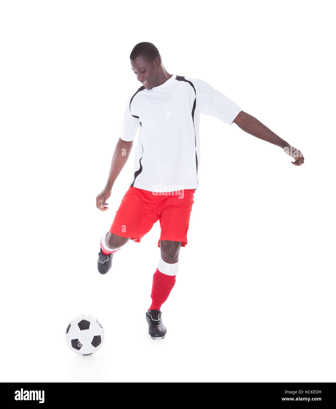 Gerne afrikanische Spieler kicken den Ball auf weißem Hintergrund Stockfoto