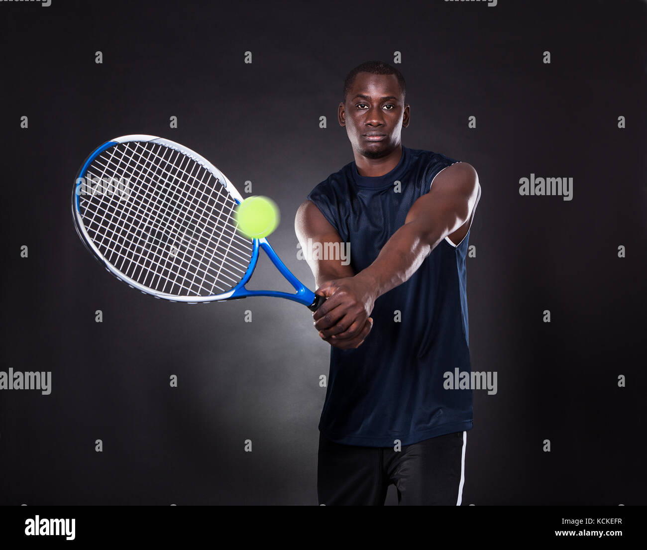 Porträt der jungen afrikanischen Mann spielt Tennis auf schwarzem Hintergrund Stockfoto