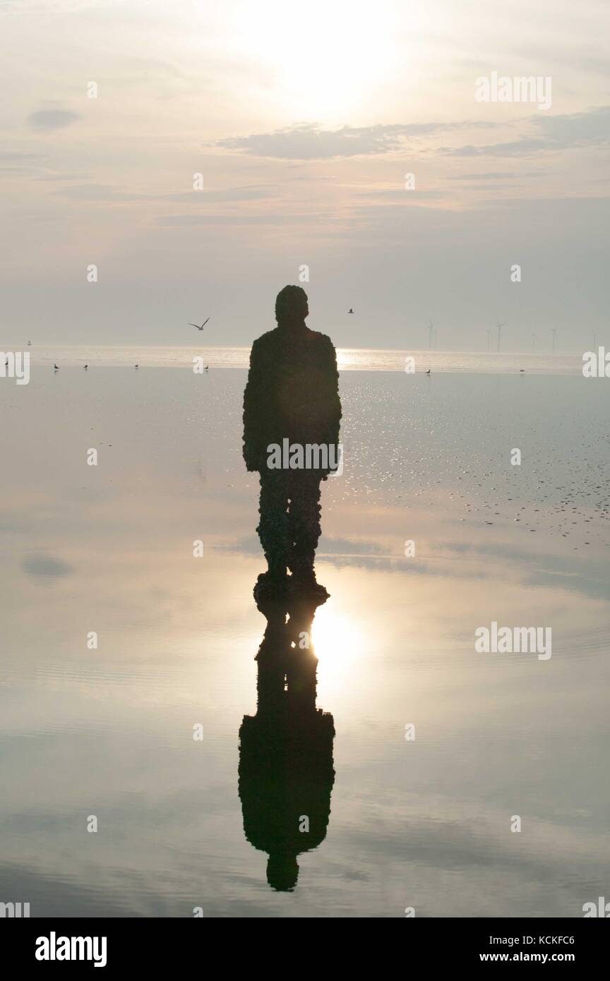 Sir Antony Gormley sculpted Abbildung reflektiert und im Sonnenuntergang silouhetted. Im gezeiten Pool. . Einen anderen Ort. Stockfoto