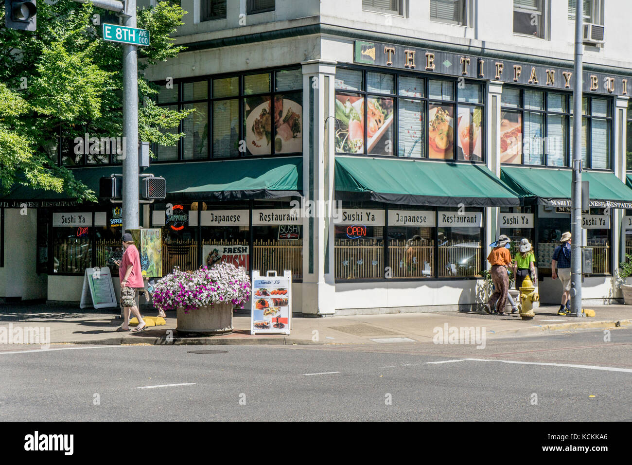 Straße Ecke Szene in Eugene Oregon mit Blumen in der Ecke pflanzmaschine als Oregonian Fußgänger für den Sommer gekleidet Samstag pass alte Innenstadt Gebäude Stockfoto