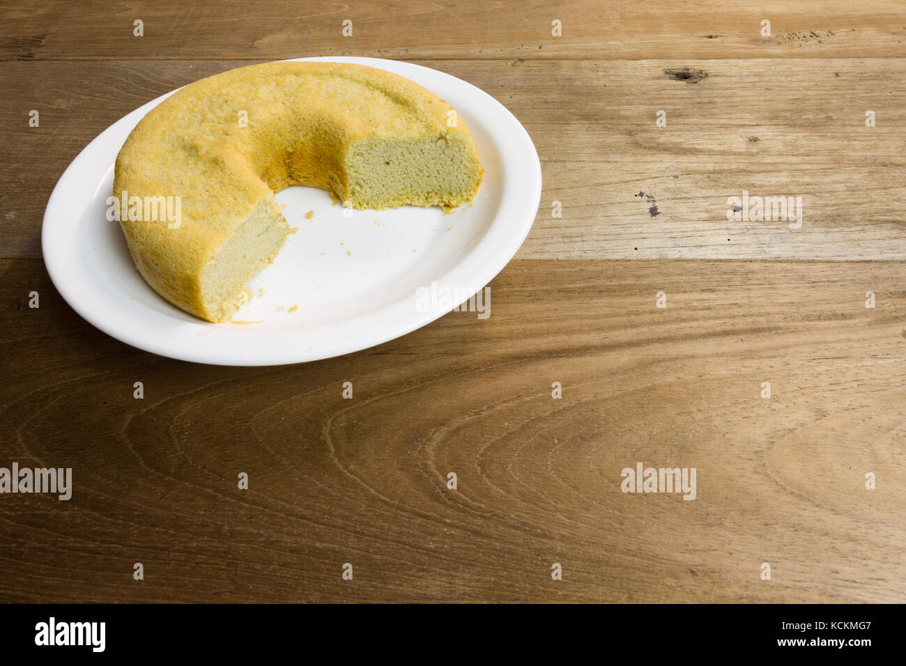 Hausgemachter Kuchen aus Baumwolle auf weißem Teller, verzehrfertig, auf rustikalem Holztisch Stockfoto