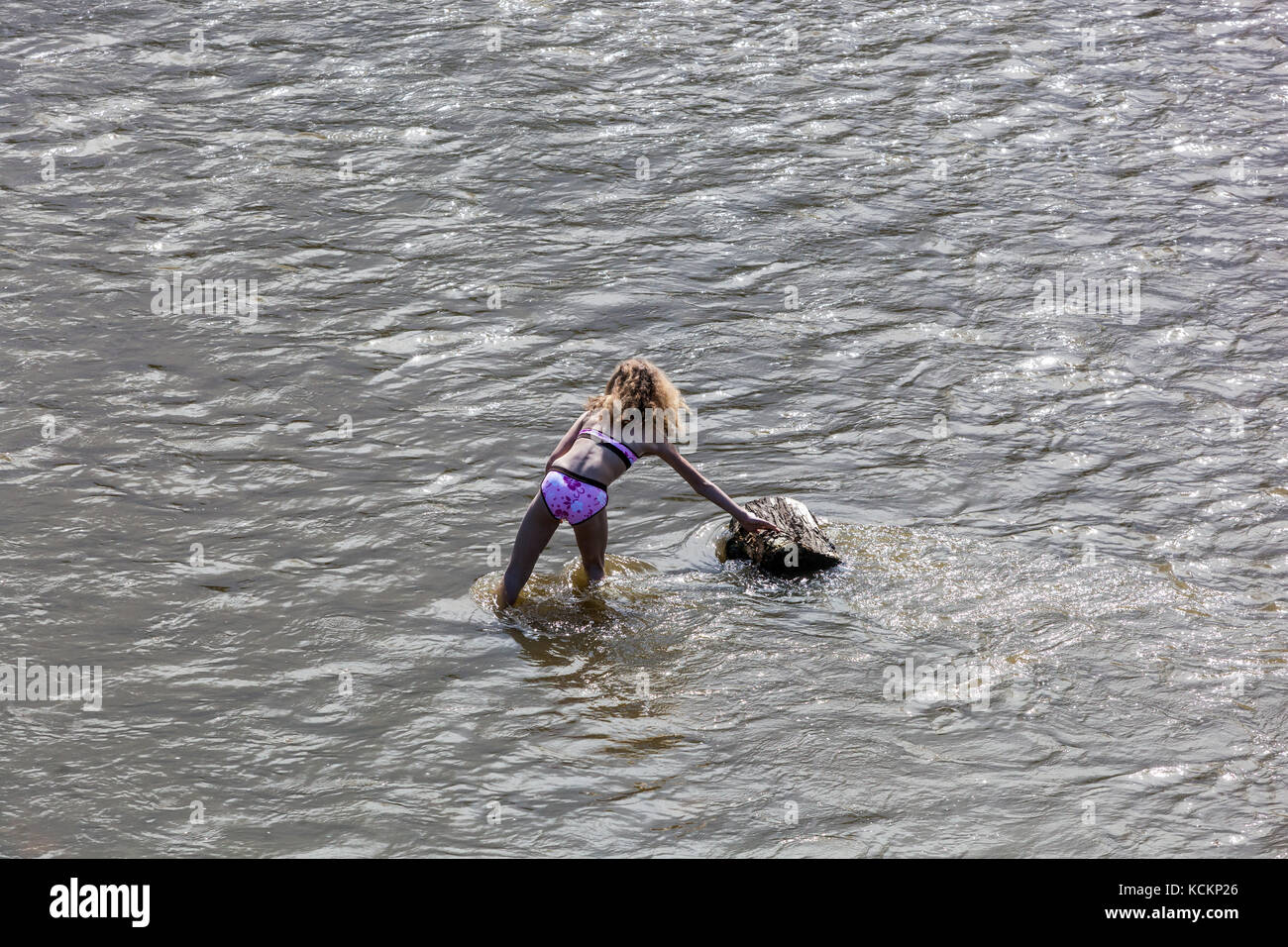 Ein Mädchen, allein im Badeanzug, der in einem Fluss steht Stockfoto