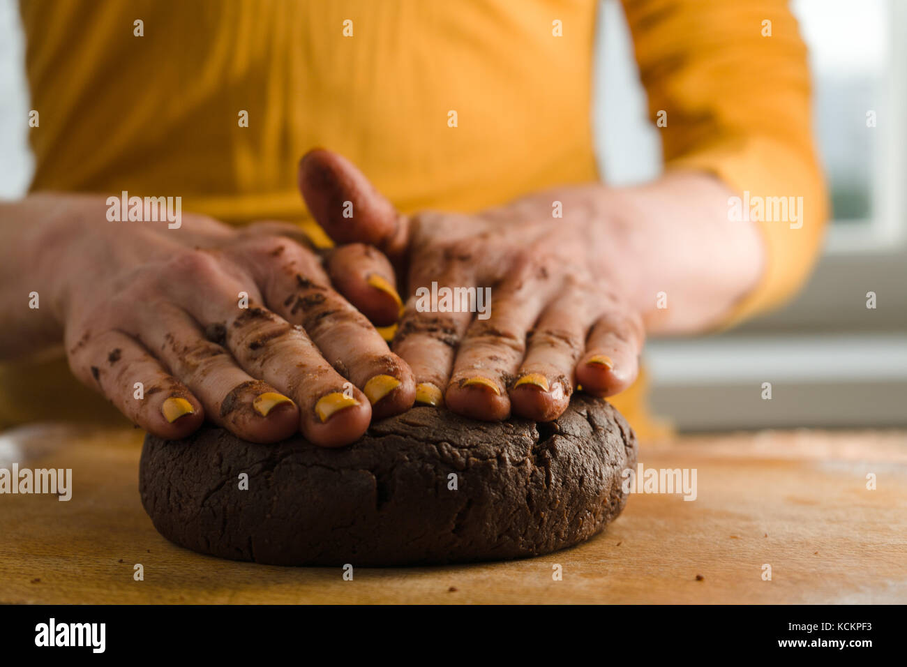 Ball von Teig und Kakao auf ein Holzbrett mit den Händen horizontale gedrückt Stockfoto