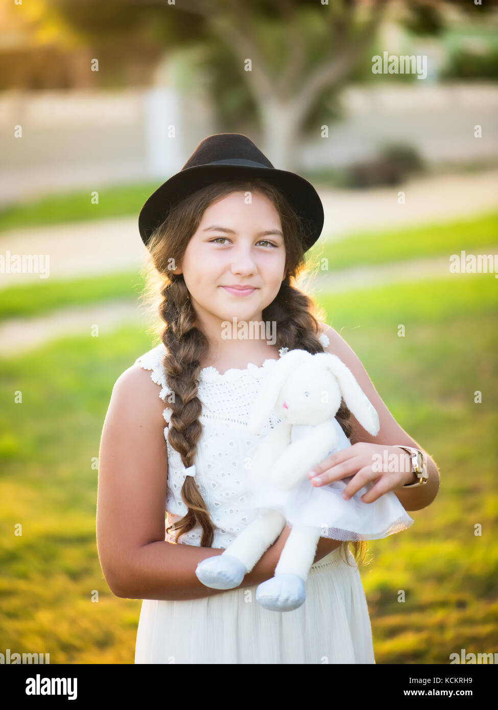 Kleines Mädchen in einem Hut mit einem Stofftier in den Händen Stockfoto