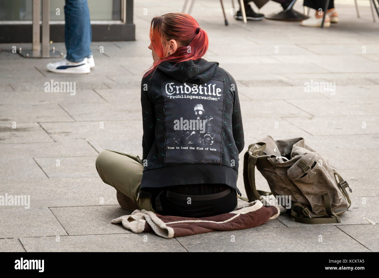 Deutsches Mädchen in Meinung T-Shirt auf der Straße sitzen (wörtliche Übersetzung: Letztes Schweigen) Stockfoto