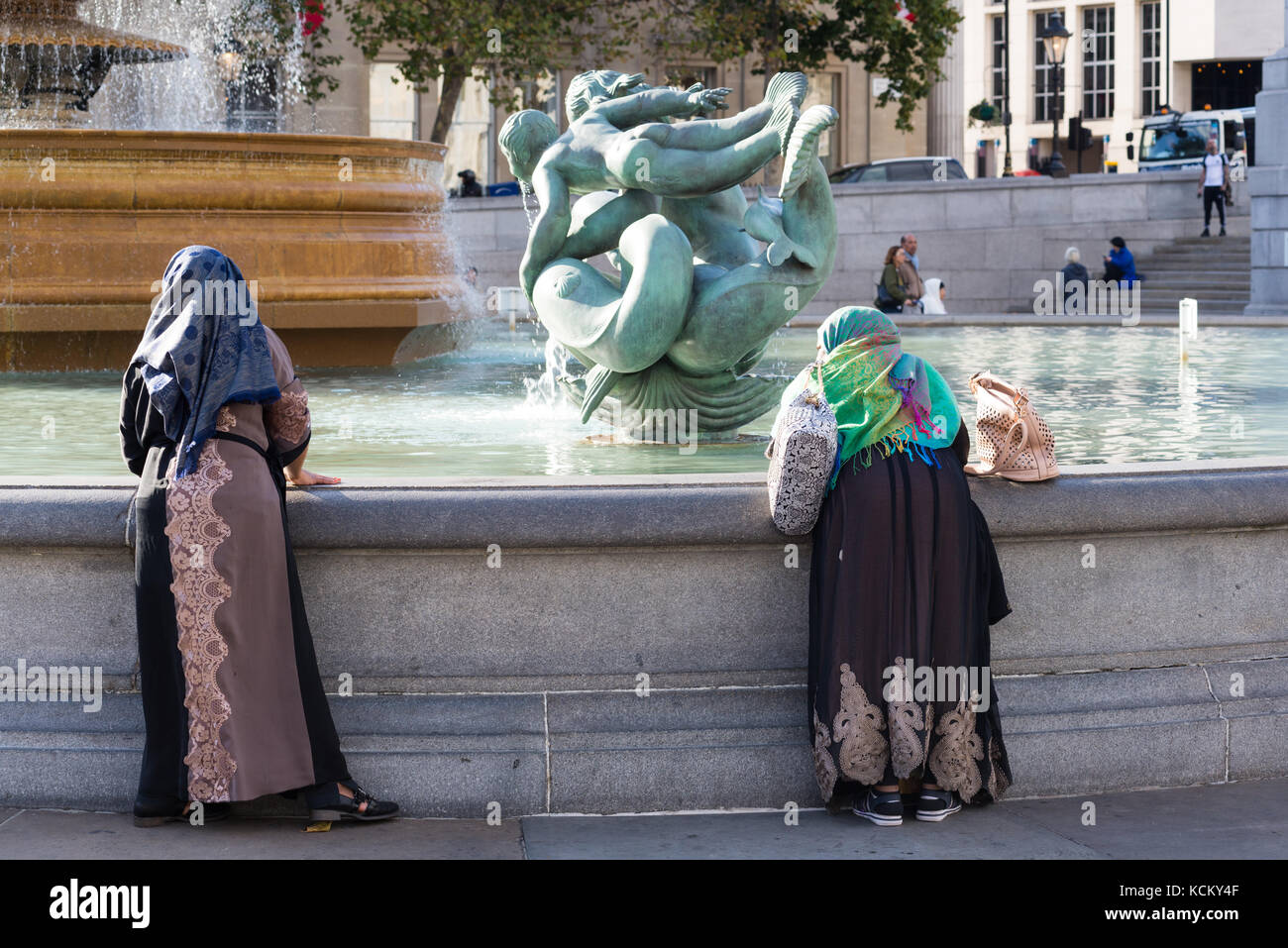 Frauen in der traditionellen asiatischen Kleid, mit Blick auf einen Brunnen am Trafalgar Square, London, England, Großbritannien Stockfoto