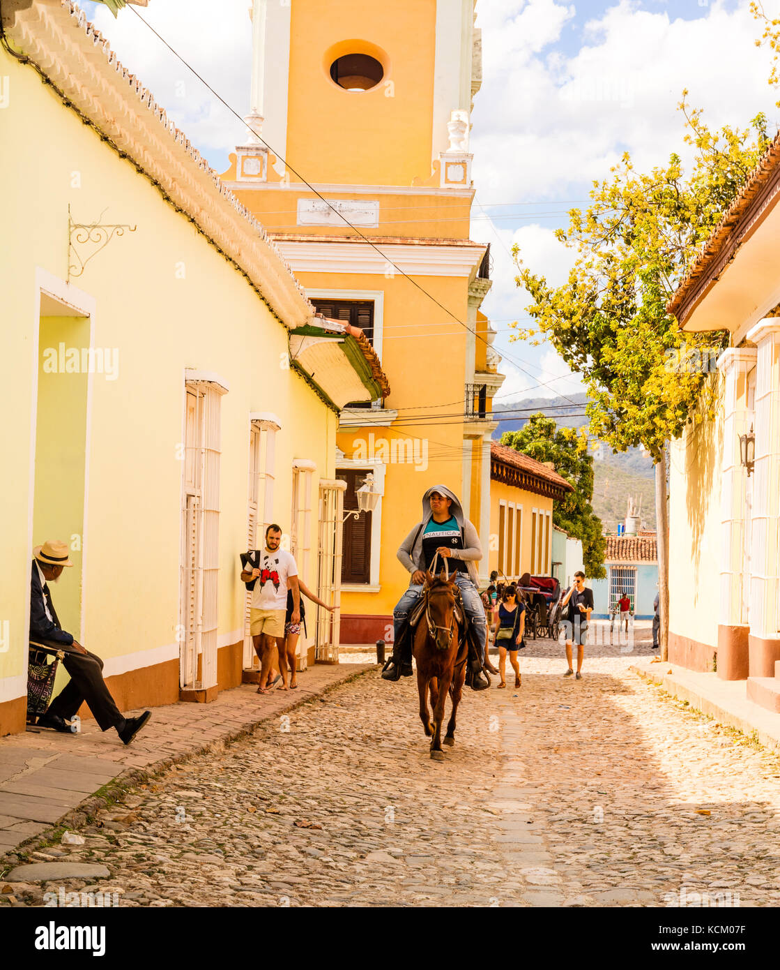 Kubanische Cowboy reitet Pferd Vergangenheit th brigtly Farbige l Häuser auf den gepflasterten Straßen von Trinidad, Kuba, Karibik Stockfoto
