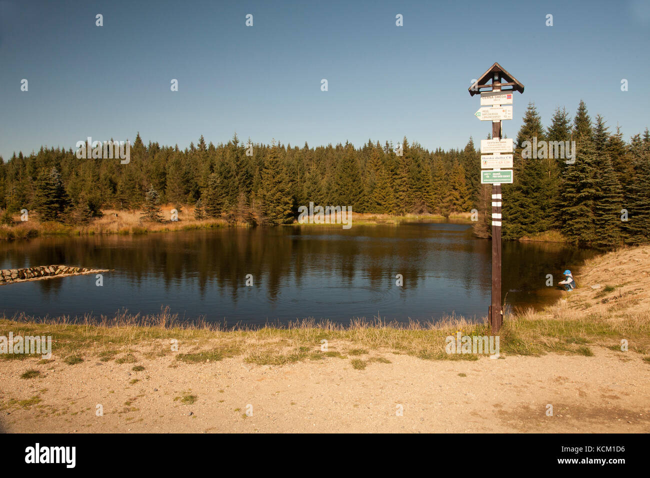 Kleiner Junge sitzt, Wasserbehälter in der Tschechischen Republik in der Natur Reservierung genannt Jizerské hory. bunten Herbstfarben an einem sonnigen Tag mit blauen Himmel Stockfoto