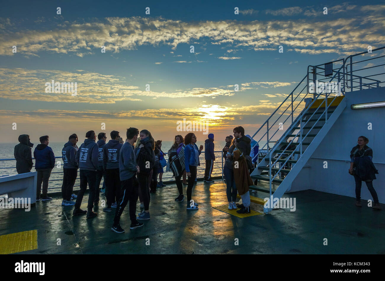 Menge von Studierenden bei Sonnenuntergang auf der Nordsee Fähre Stockfoto