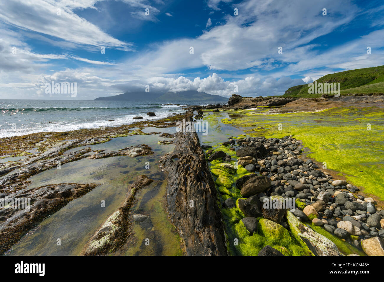 Basaltdeich Felsformationen am Strand an der Bucht von Laig, auf der Isle of Eigg, Schottland, Großbritannien. Dahinter ist die Isle of Rum. Stockfoto