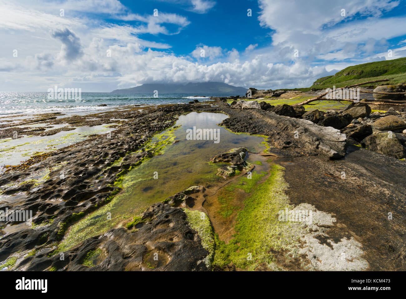 Felsformationen am Strand in der Bucht von Laig, auf der Isle of Eigg, Schottland, Großbritannien. Dahinter ist die Isle of Rum. Stockfoto