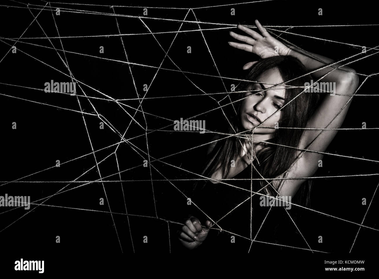 Junge Frau verwickelt Das Netz der Seile über schwarzen Hintergrund Stockfoto