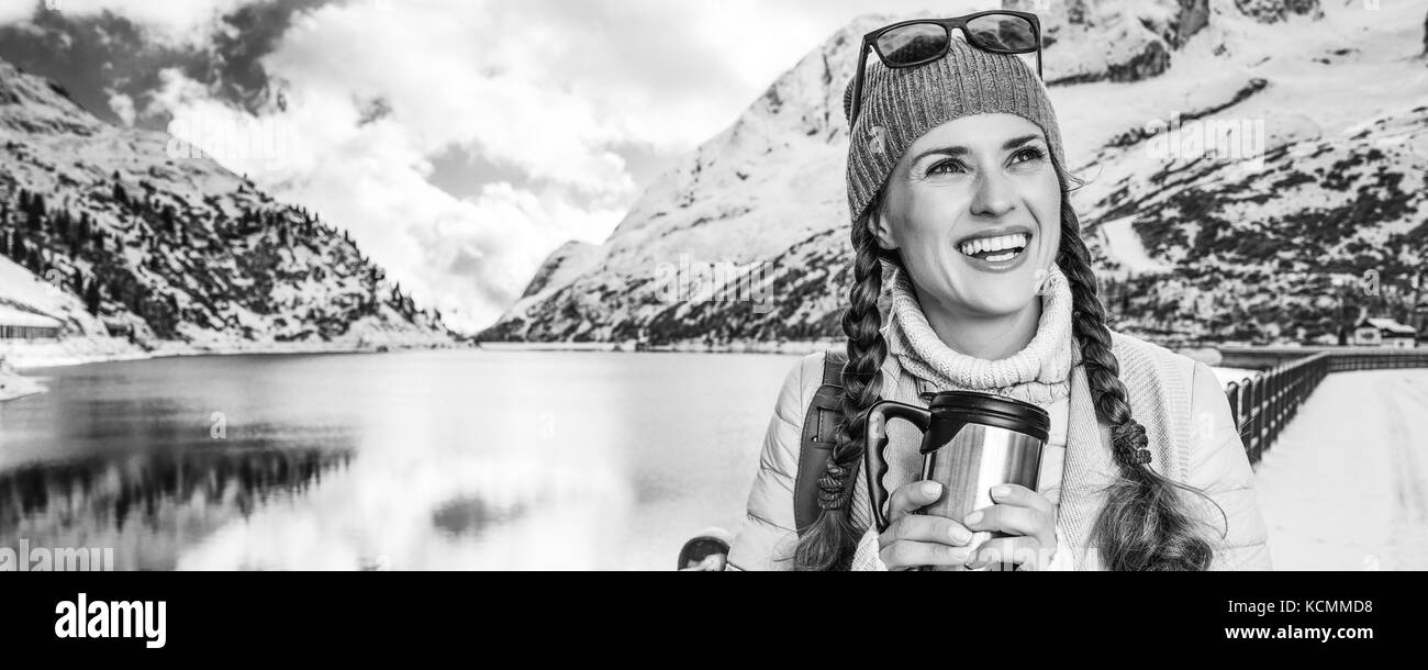 Winter auf höherer Ebene Spaß. Happy Elegant touristische Frau in der Berglandschaft mit See in Alto Adige, Italien mit thermos Travel Mug l Stockfoto