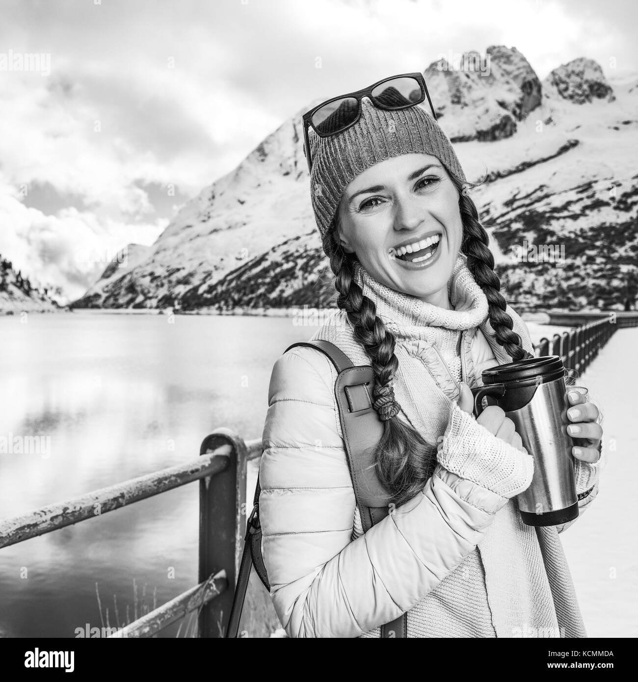 Winter auf höherer Ebene Spaß. Portrait von Happy stilvolle touristische Frau gegen Berglandschaft mit See in Südtirol, Italien mit thermos Travel Stockfoto