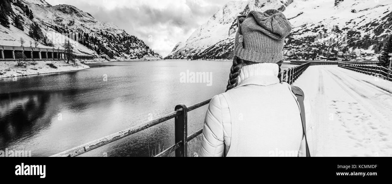 Winter auf höherer Ebene Spaß. Von hinten stilvolle Frau gegen Berglandschaft mit See in Alto Adige, Italien Stockfoto