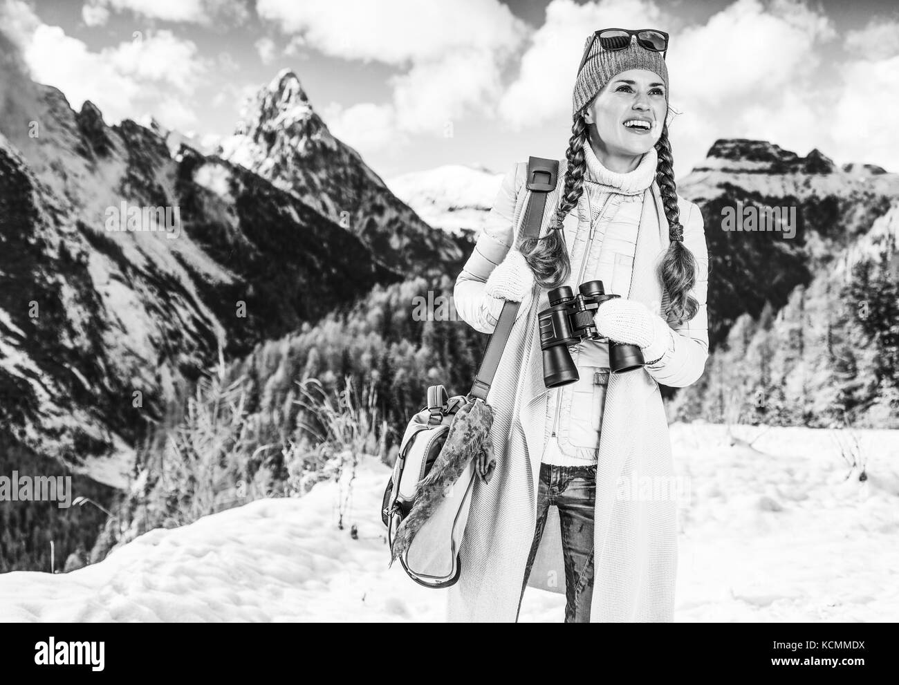 Winter auf höherer Ebene Spaß. lächelnden jungen Reisenden Frau gegen Bergwelt in Südtirol, Italien mit dem Fernglas in die Ferne suchen Stockfoto