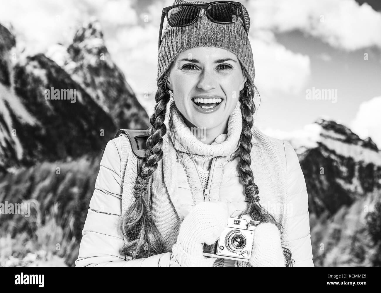 Winter auf höherer Ebene Spaß. Portrait von lächelnden Elegante touristische Frau gegen Bergwelt in Südtirol, Italien mit retro Foto Kamera Stockfoto