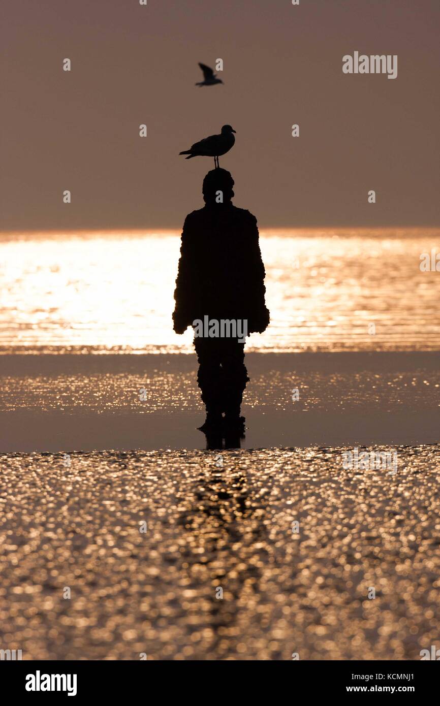 Sir Antony Gormley sculpted Abbildung silouhetted mit Flügeltüren bei Sonnenuntergang, einen anderen Ort. Stockfoto