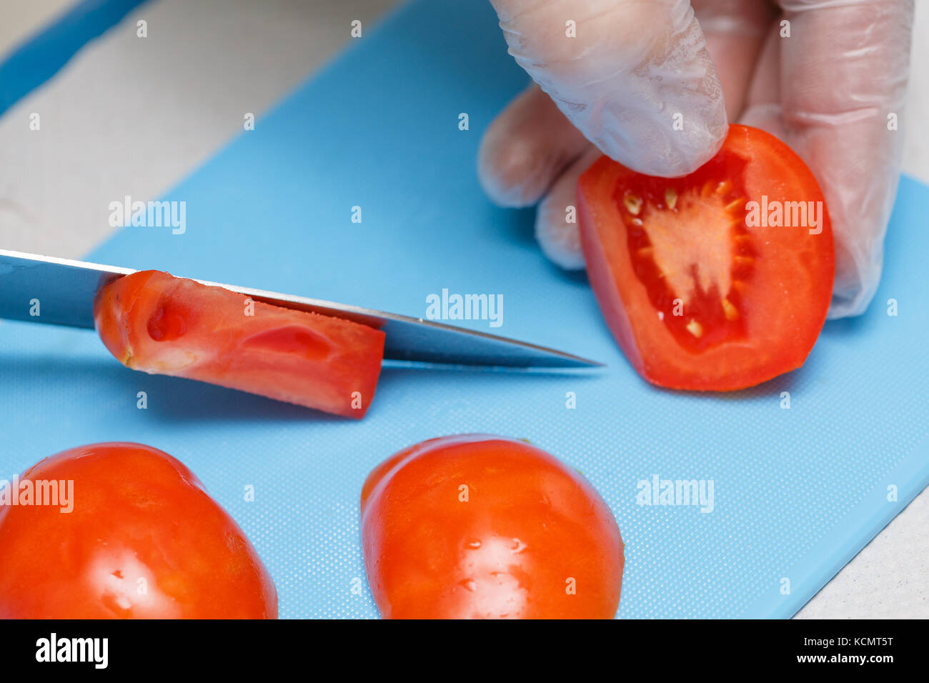 Koch Hand und Messer zum Schneiden oder Schneiden rote Tomaten Stockfoto