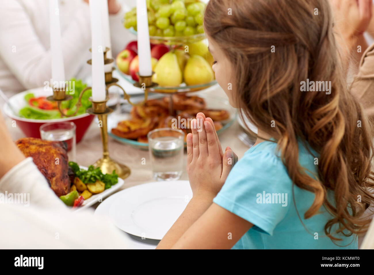 Mädchen mit Familie Essen und zu Hause beten Stockfoto