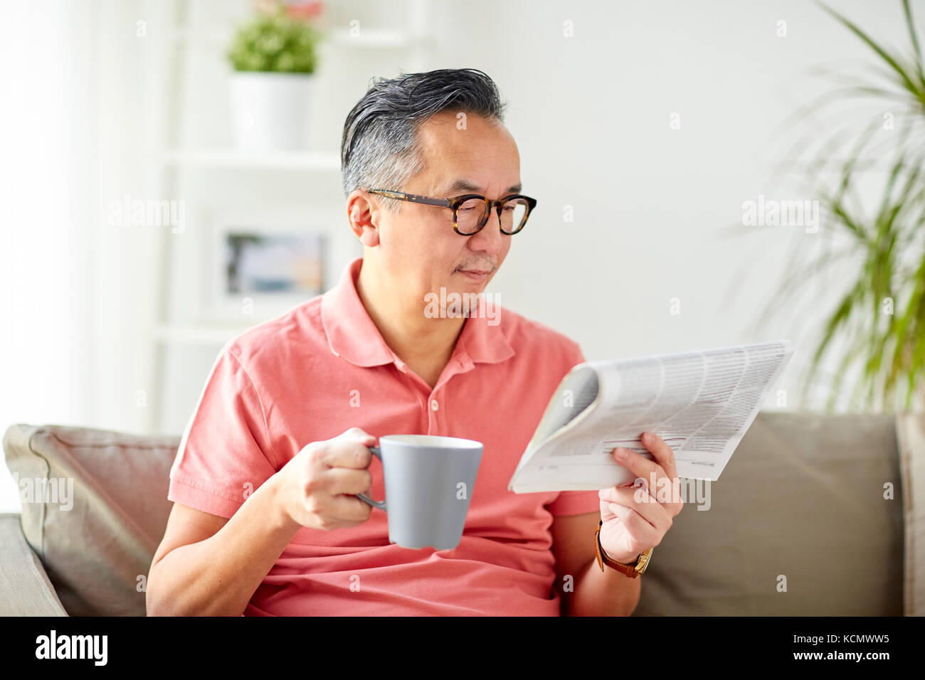 Man Kaffee trinken und lesen Zeitung zu Hause Stockfoto