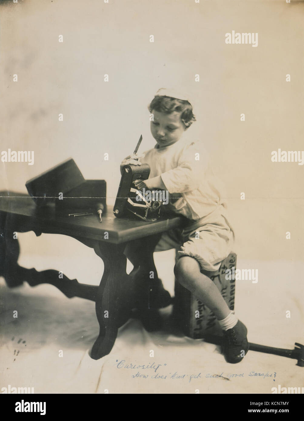 „Neugier wie bekommt Dad so gute Schnappschüsse?“ ist ein Foto, das einen Moment kindlichen Staunens aufnimmt und die Kunst der Fotografie und ihr Können in Frage stellt. Stockfoto