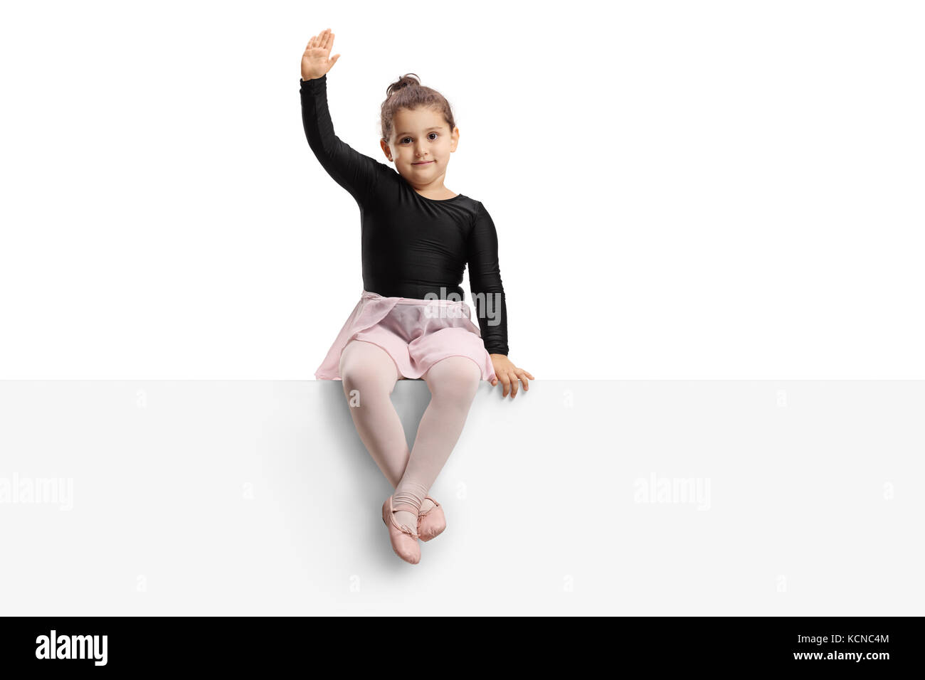 Kleine Ballerina sitzen auf einem Panel und winken in die Kamera auf weißem Hintergrund Stockfoto