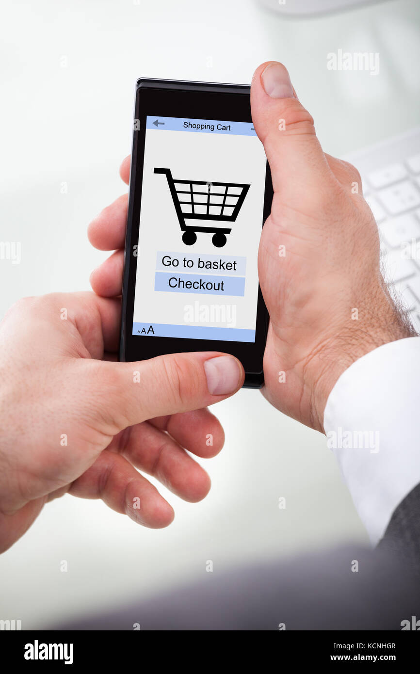Geschäftsmann hält Mobile mit Online-Shopping-Anwendung auf einem Bildschirm Stockfoto