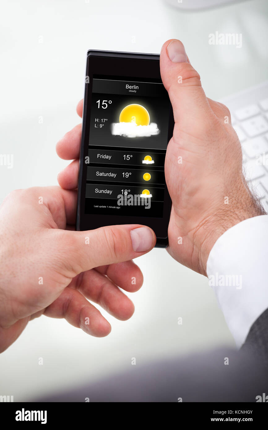 Nahaufnahme eines Geschäftsmannes suchen Wettervorhersage auf Handy Stockfoto