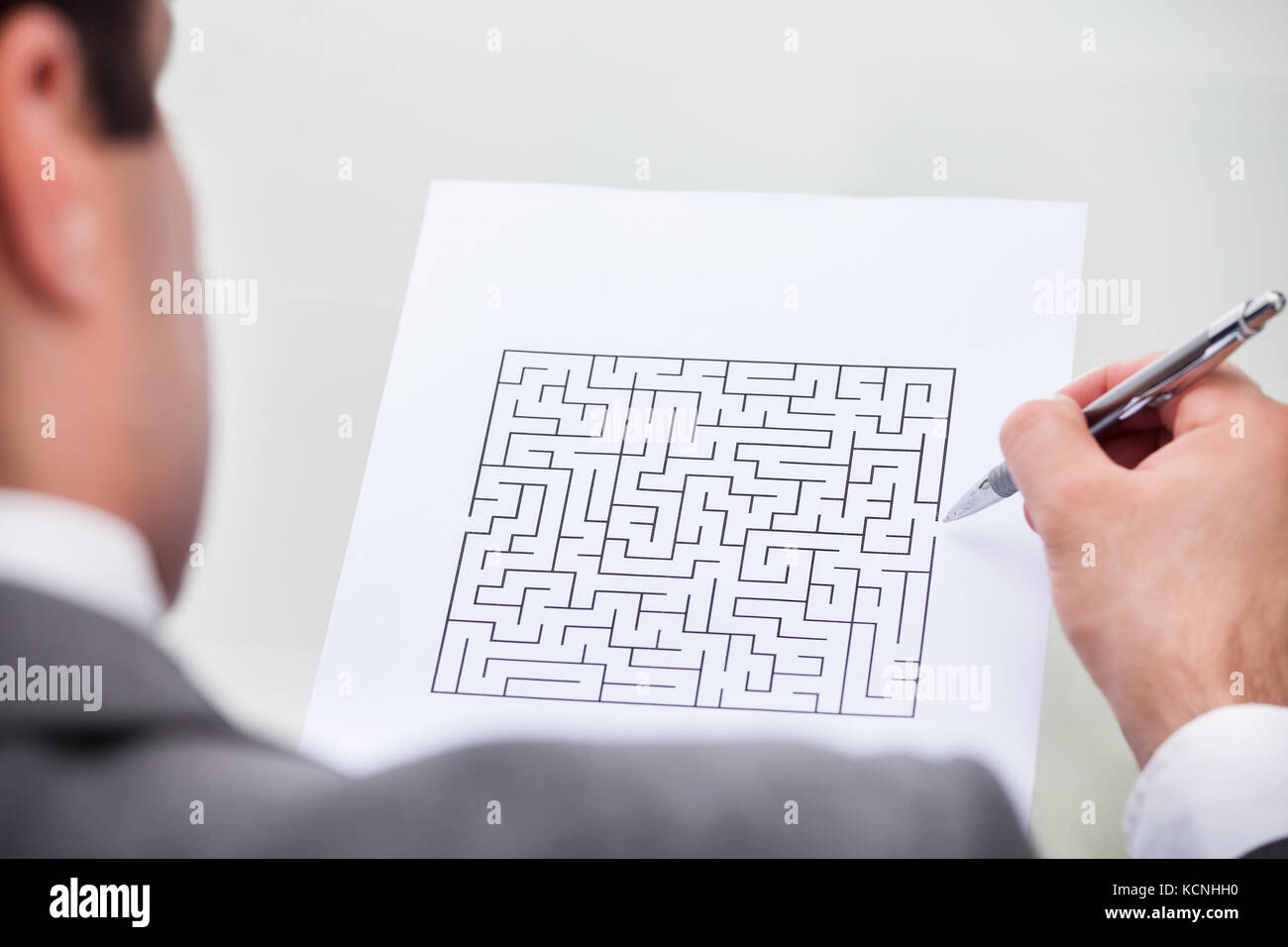 Nahaufnahme eines Geschäftsmannes betrachten Labyrinth Puzzle mit Stift Stockfoto