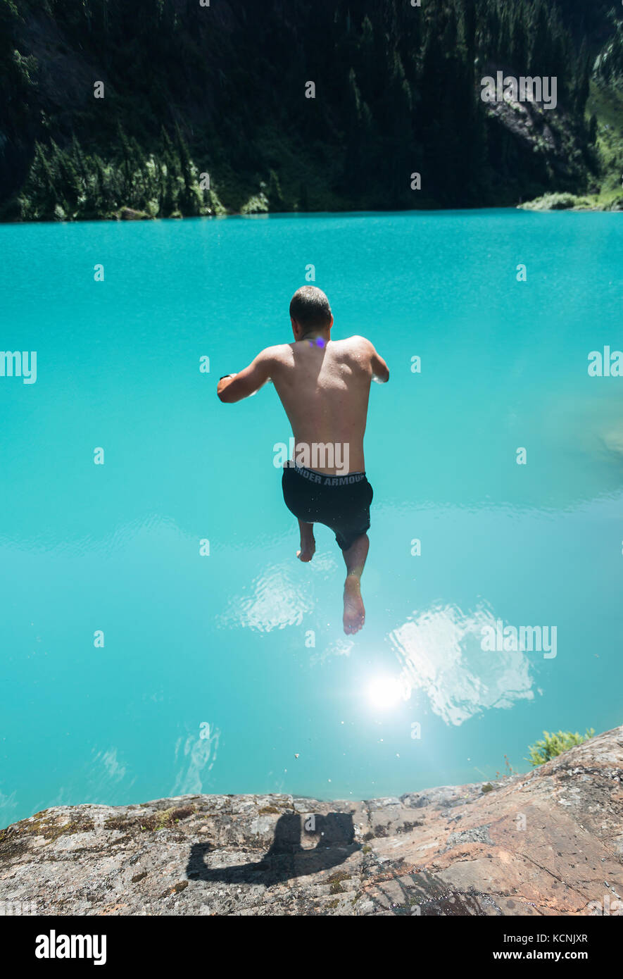 Ein Jugendlicher nimmt ein Bad im kühlen smaragdgrünen Wasser beim Wandern zu Jahrhundert sam See im Strathcona Park, Vancouver Island, British Columbia, Kanada Stockfoto