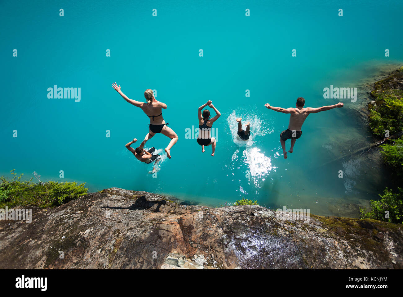 Fünf Freunde tauchen Sie ein in die türkisblauen Fluten des Jahrhunderts sam See im Strathcona Park, Vancouver Island, British Columbia, Kanada Stockfoto