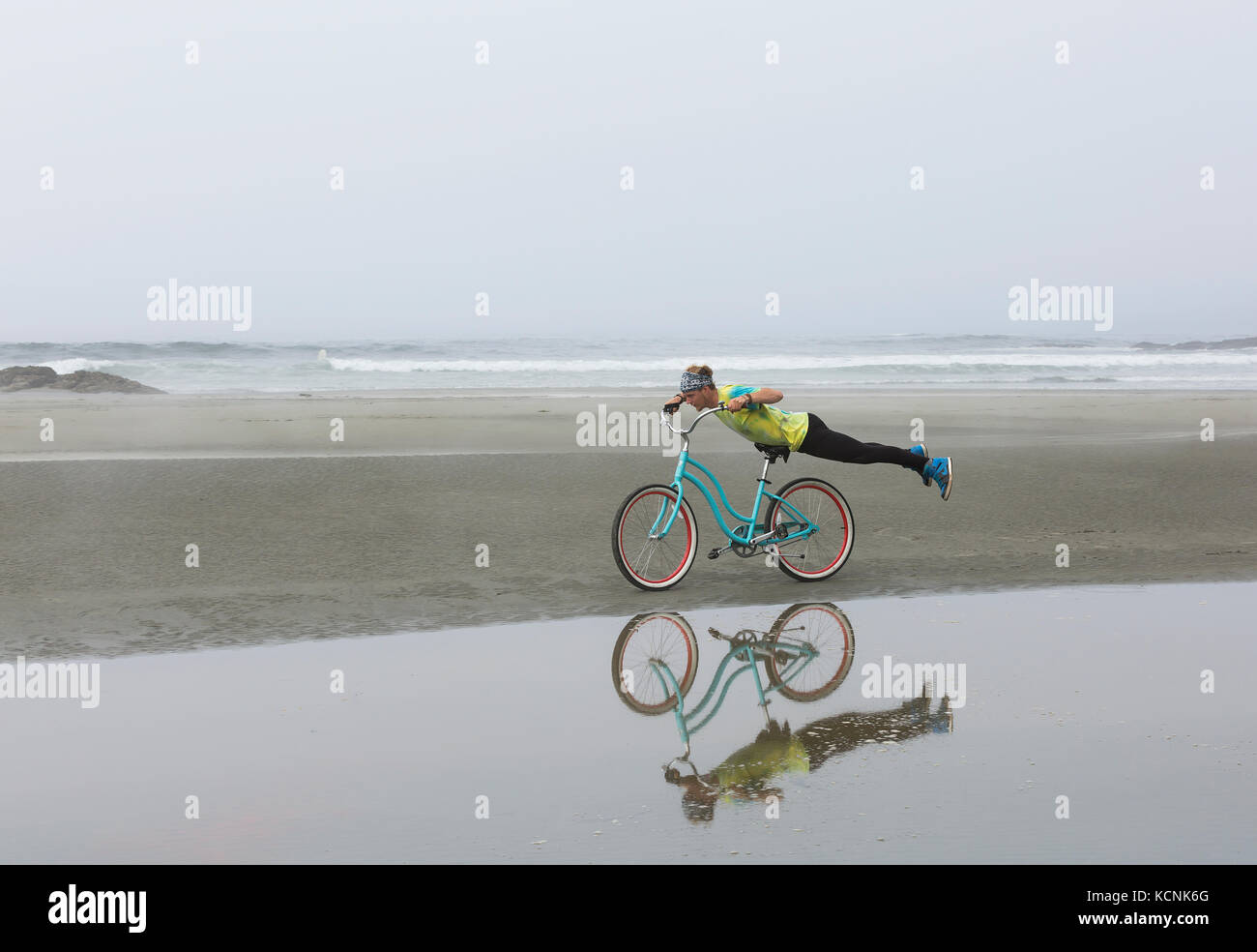 Ein Reiter mit einem tie dye t-shirt spielt auf seinem Beach Cruiser während auf Chesterman Beach. Tofino, Vancouver Island, British Columbia, Kanada. Stockfoto