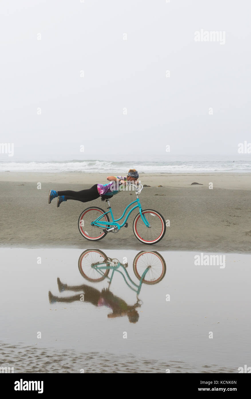 Ein Reiter mit einem tie dye t-shirt spielt auf seinem Beach Cruiser während auf Chesterman Beach. Tofino, Vancouver Island, British Columbia, Kanada. Stockfoto