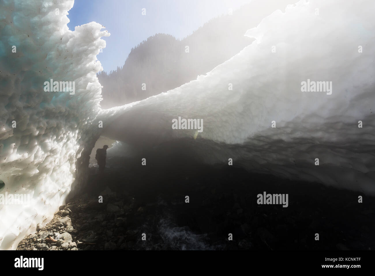 Ein Wanderer geht durch eine schneehöhle am Sockel des Jahrhunderts sam See, Strathcona Park, Vancouver Island, British Columbia, Kanada. Stockfoto