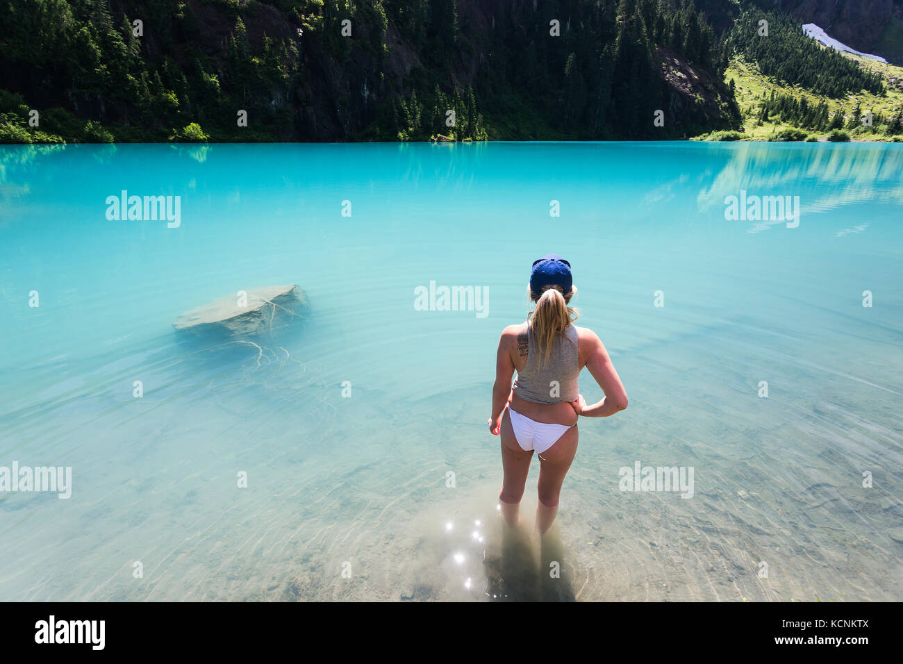 Eine junge Frau entspannt sich im türkisfarbenen Wasser des Jahrhunderts sam See im Strathcona Park, Vancouver Island, British Columbia, Kanada Stockfoto