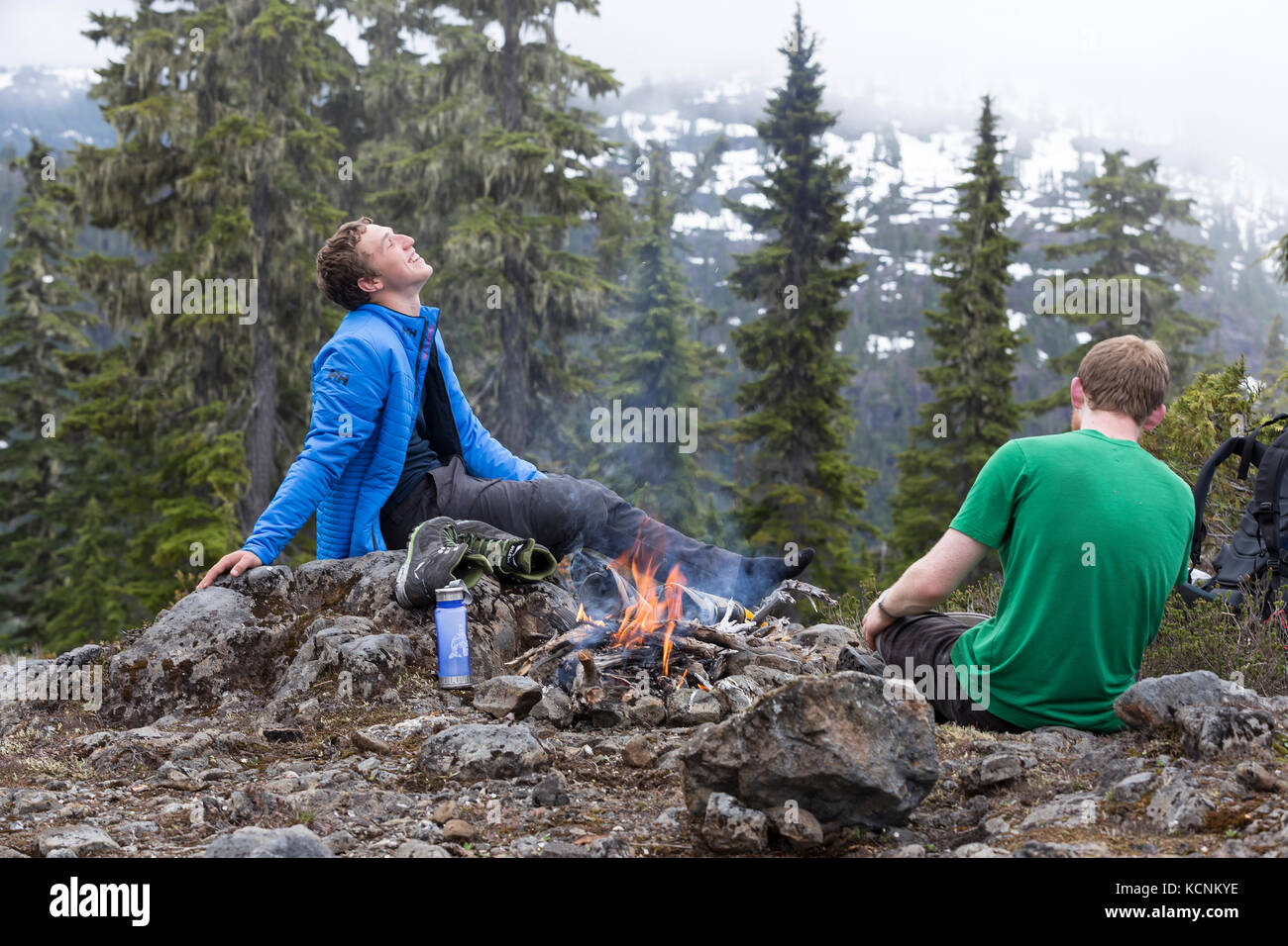 Zwei Freunde teilen ein Lachen an einem Lagerfeuer beim Wandern auf Lee Plateau. Vancouver Island, British Columbia, Kanada Stockfoto