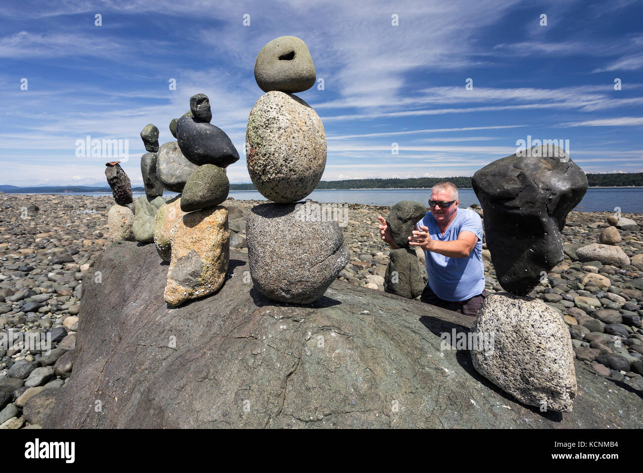 Ein praktizierender von der Kunst des Rock balancing hat ein Feld Tag bei Ebbe an der Küste der Discovery Passage, Campbell River, Vancouver Island Stockfoto