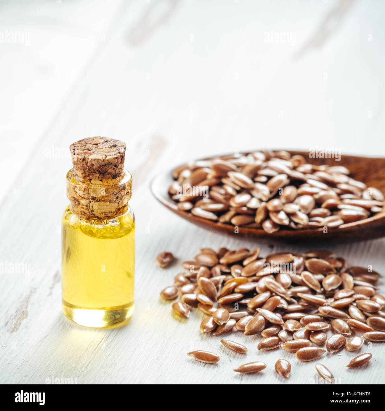 Brauner Leinsamen in Löffel und Leinsamenöl in Glasflasche auf weißem Holz- Hintergrund. Leinöl ist reich an Omega-3-Fettsäuren. Kopieren Sie Platz. Platz Stockfoto