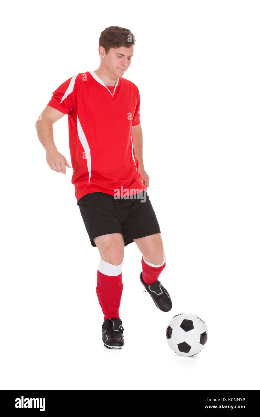 Porträt des jungen Fußballer treten Ball Over White Background Stockfoto